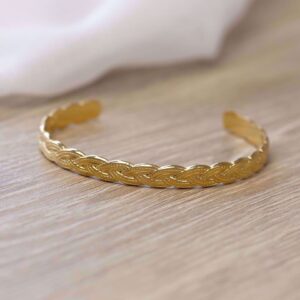 Flettet armring i PVD‑guldfarvet rustfrit stål.